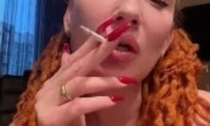 Mistress smokes a cigarette, exhaling the smoke right in your face